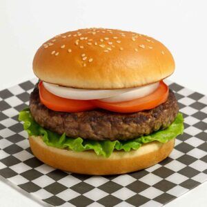 Hyper-realistic 1/2 lb Hamburger on check deli paper with a juicy half-pound beef patty, fresh lettuce, tomato slices, and onion rings on a sesame seed bun. Perfect hamburger or lunch near me in Newport News.