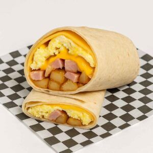 A hyper-realistic image of a Classic Egg Wrap made with a plain flour tortilla, filled with scrambled eggs, diced ham, crispy home fries, and melted American cheese, served on black-and-white checkered deli paper against a clean white background.