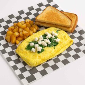 A hyper-realistic image of a Greek Style Omelet Platter featuring a fluffy omelet topped with spinach and feta cheese, served with golden home fries and toasted bread on black-and-white checkered deli paper. Perfect for anyone searching for Breakfast near me in Newport News.